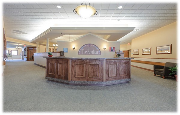 A well-lit hotel reception area featuring a large wooden desk.