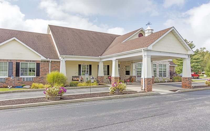 A well-maintained building entrance with landscaped surroundings and a paved driveway.