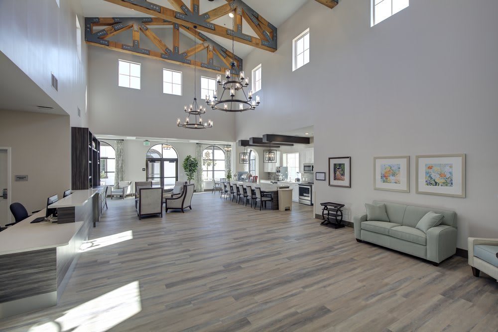 A spacious and modern living room with high ceilings, featuring elegant chandeliers and wooden beams.