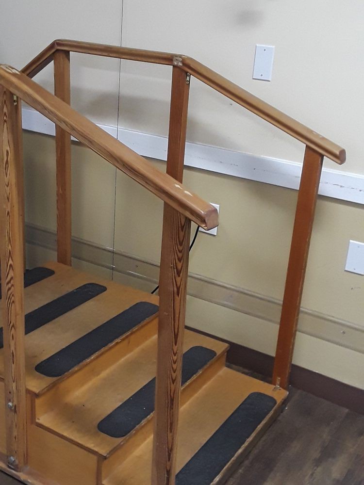 A small indoor wooden staircase with safety strips and handrails.