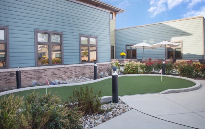 A well-maintained outdoor area with a green lawn and surrounding plants beside a modern building.