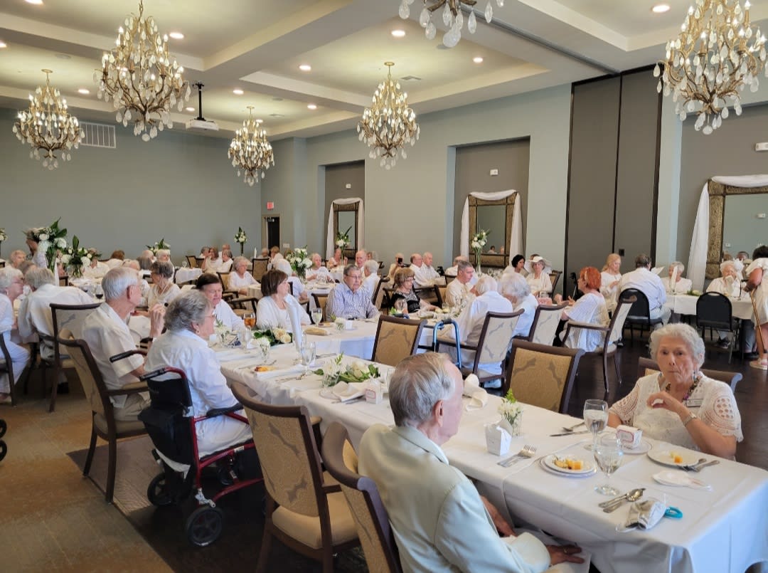 A formal banquet event with guests seated at long tables in an elegantly decorated room.