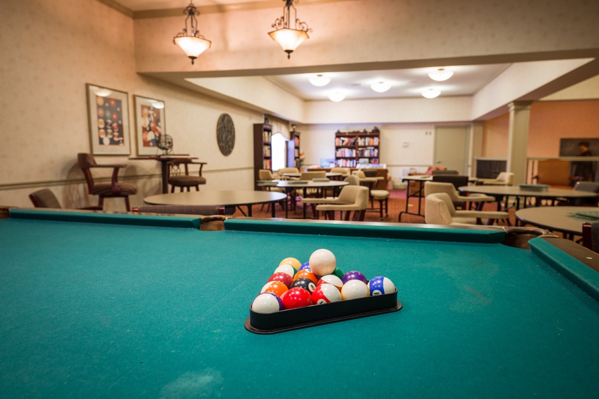A billiard table set up in a cozy game room with seating and ambient lighting.