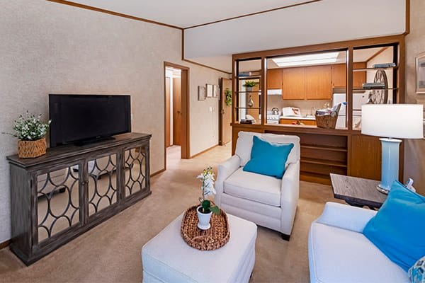 A cozy living room with a view into the kitchen, featuring comfortable seating and modern decor.