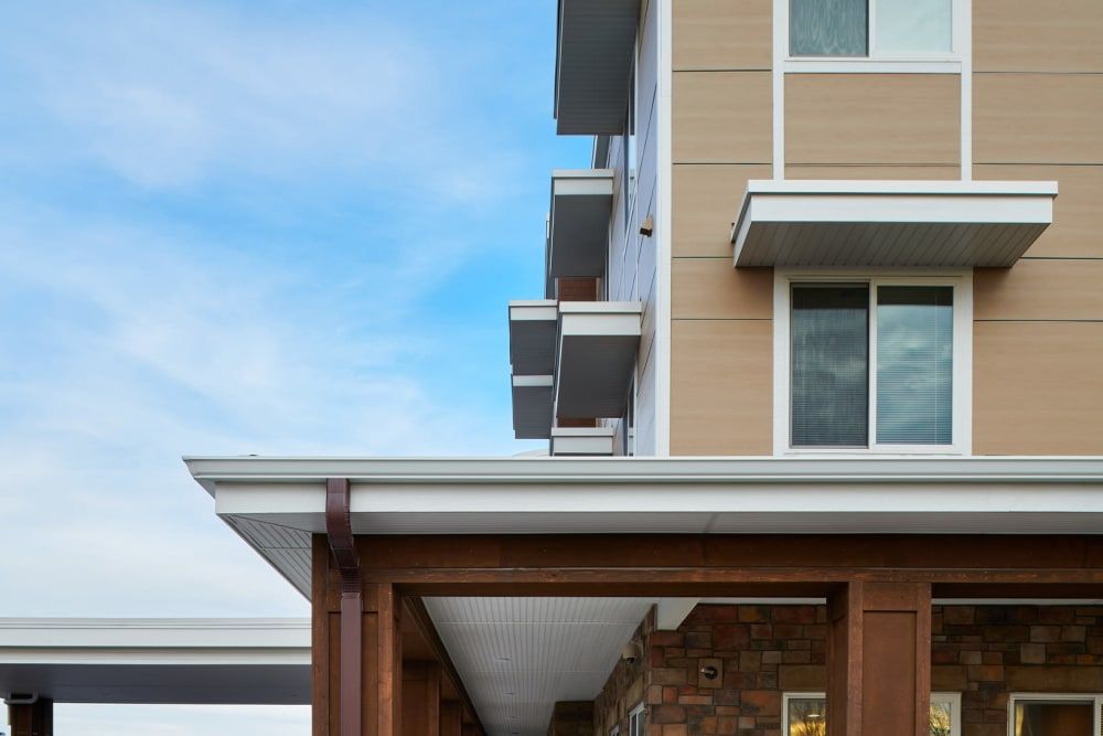 A modern building exterior featuring multiple balconies and large windows under a clear blue sky.