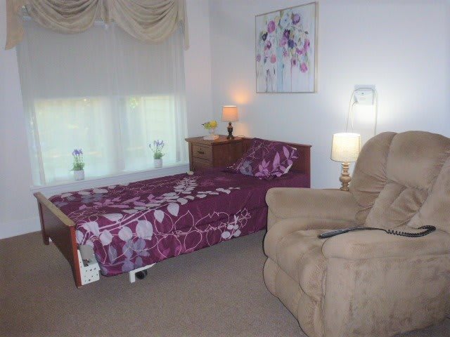 A cozy bedroom with a single bed, an armchair, and soft lighting.