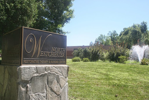 A bronze plaque sign marking a location amidst lush greenery.