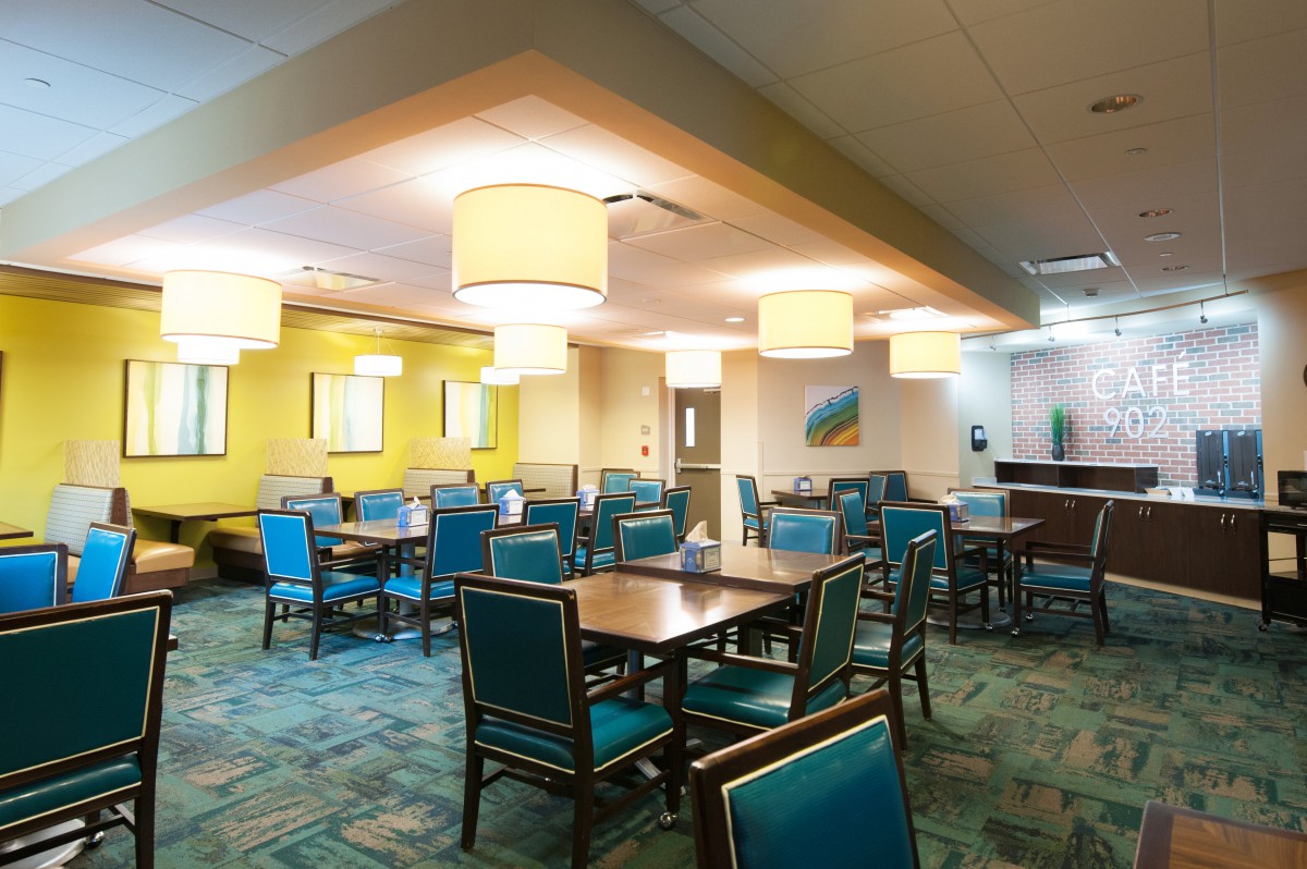 A modern dining area with teal chairs and warm lighting.