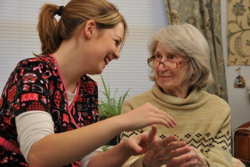 A caregiver engages in a friendly conversation with an elderly woman.