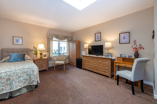 A cozy and well-furnished bedroom featuring a bed, a television unit, and ample natural light.