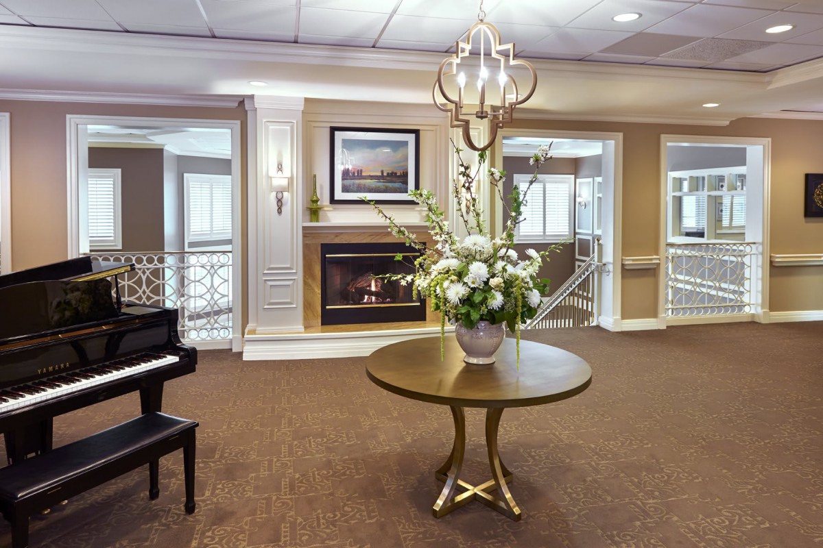 A sophisticated lobby featuring a grand piano, floral centerpiece, and a cozy fireplace.