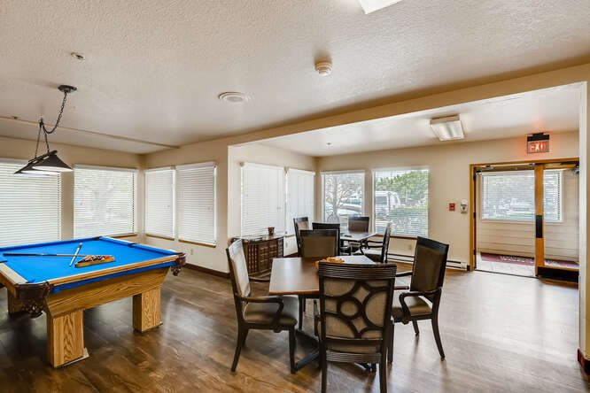 A bright game room featuring a pool table and several seating areas with large windows.