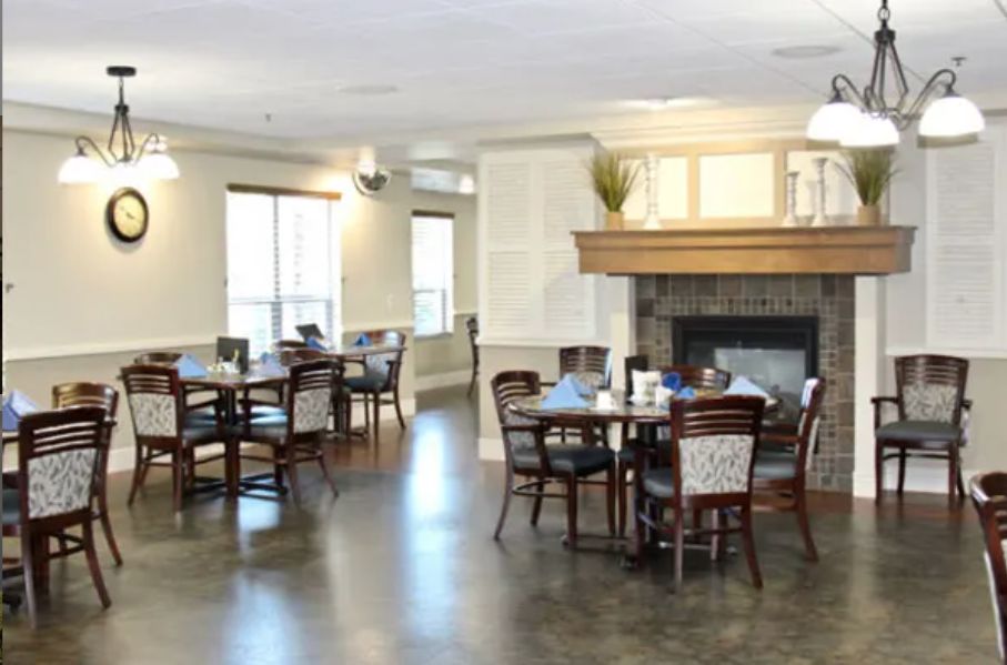 A cozy dining area with tables and chairs arranged around a central fireplace.