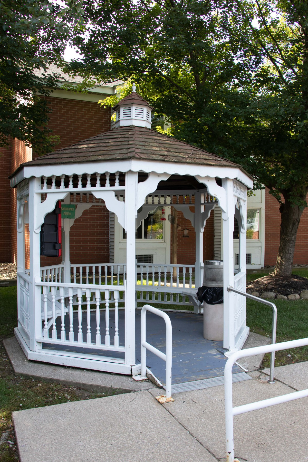 A white gazebo situated in a garden setting, surrounded by greenery.
