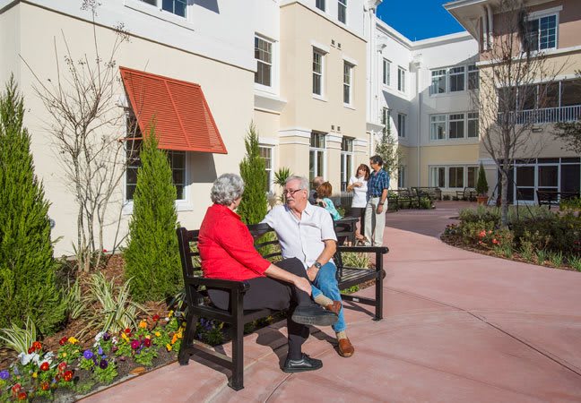 Seniors enjoying a sunny day outside at a retirement community.