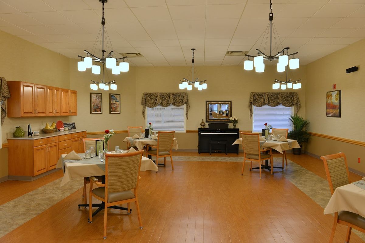 A spacious and well-lit dining room with neatly arranged tables and chairs, featuring elegant lighting fixtures and decorative elements.