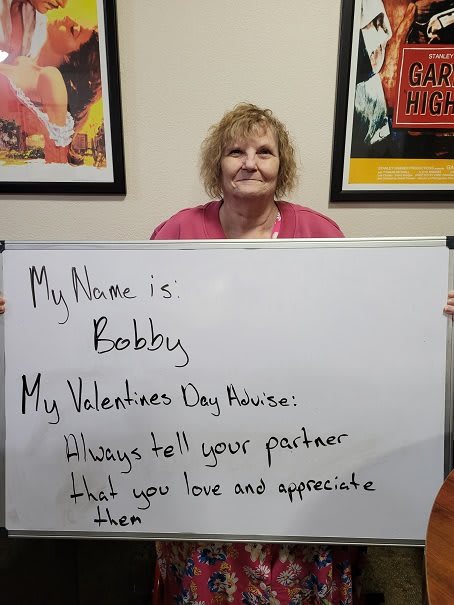 A person holding a whiteboard with Valentine's Day advice.