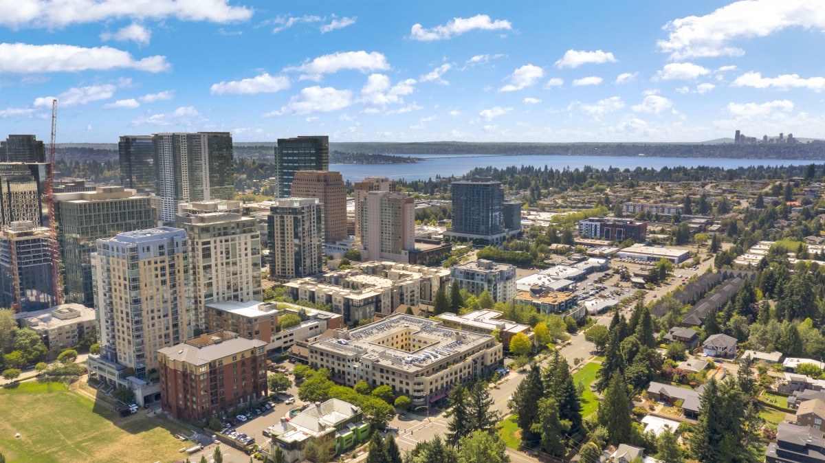 A vibrant aerial view of an urban cityscape featuring tall buildings and a nearby lake under a clear blue sky.