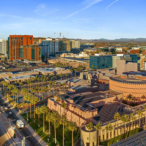 A vibrant view of a modern urban landscape showcasing a mix of contemporary buildings and palm trees under a clear blue sky.