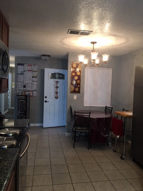 Cozy kitchen and dining area with a table and chairs under a bright lighting fixture.