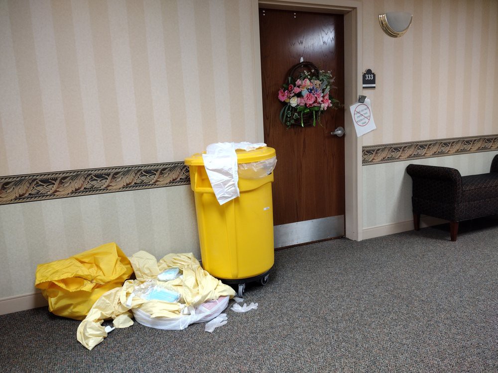 A hospital hallway with a yellow laundry bin and a decorated door.