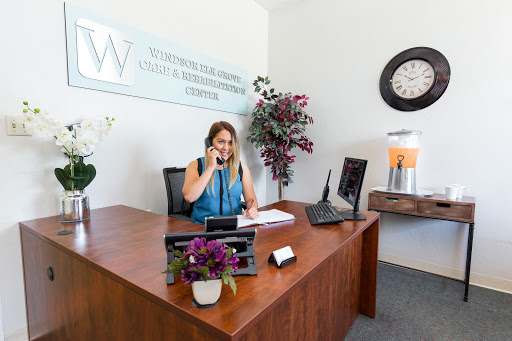 A receptionist engaging in a phone call at a modern office desk, surrounded by decorative plants.