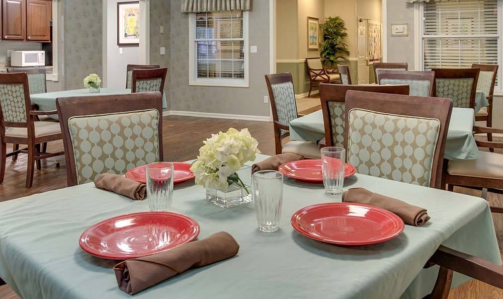 Elegantly set dining table with red plates and flowers.