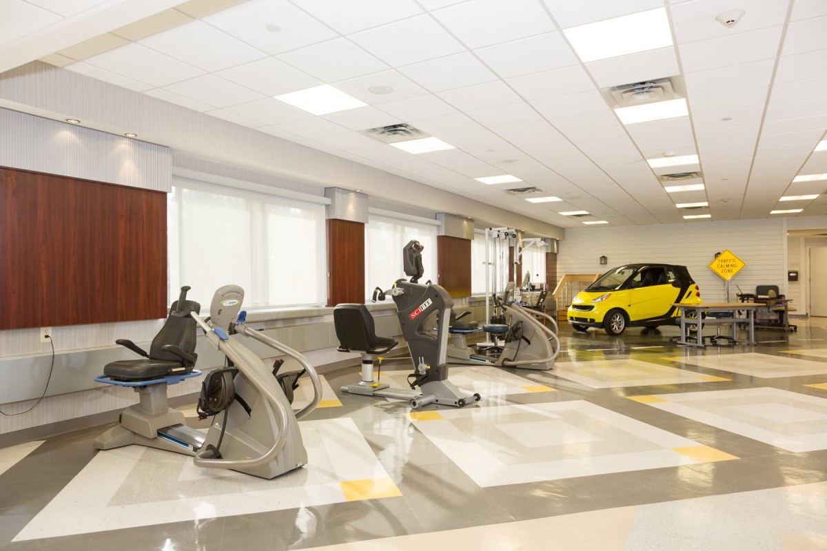Rehabilitation center with exercise equipment and a small car for therapy purposes.