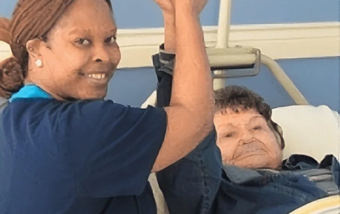 A healthcare worker assists an elderly patient during a physical therapy session.