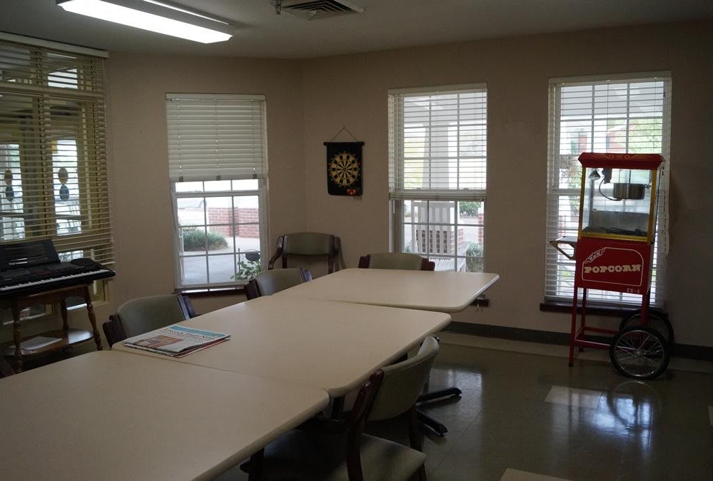 A meeting room with a large table and several chairs, featuring windows that let in natural light.