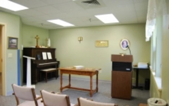 A small chapel with a piano, podium, and rows of chairs.