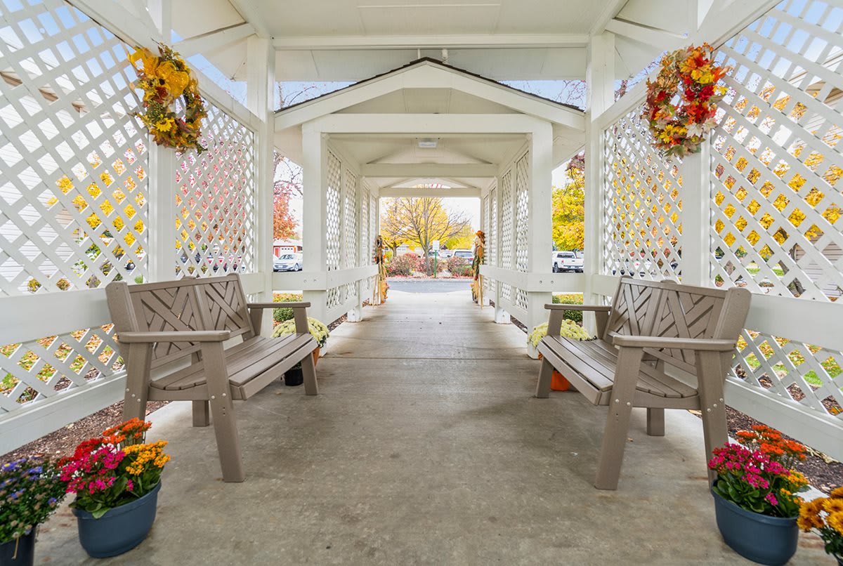 A beautifully decorated gazebo walkway adorned with autumn wreaths and surrounded by vibrant fall colors.