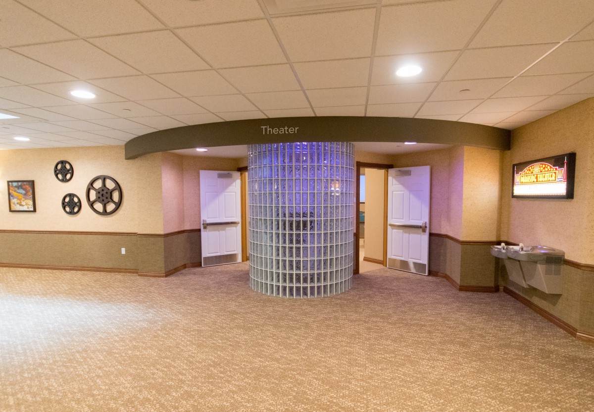 The entrance to a theater lobby featuring movie reel decorations and modern lighting.