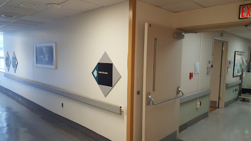 A corridor in a hospital with directional signage indicating the path.