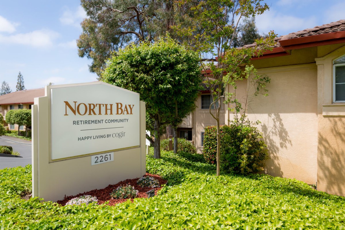A view of the North Bay apartment complex entrance with a sign and surrounding greenery.