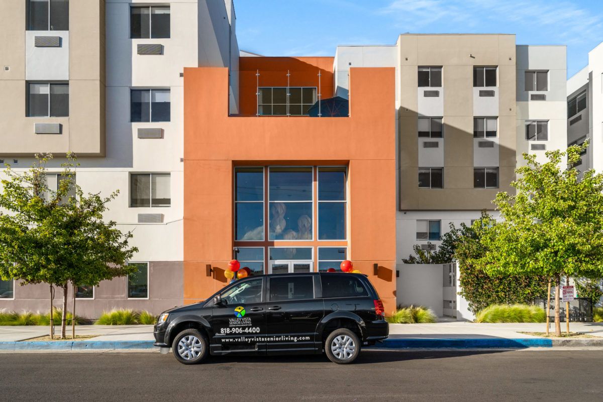 A black SUV parked in front of a modern, multicolored building.