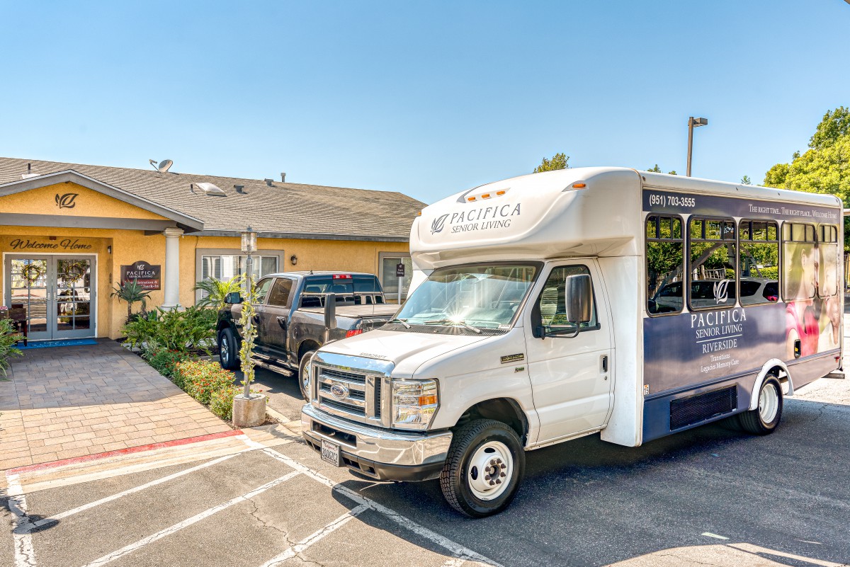 A shuttle bus parked in a lot outside a building on a sunny day.
