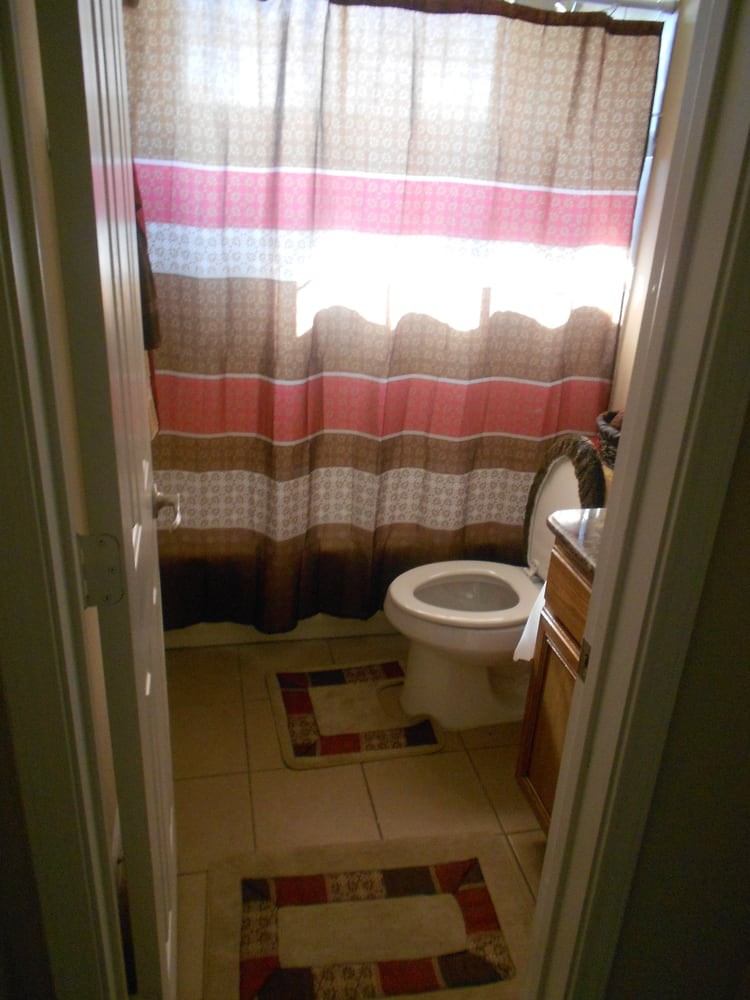 A small bathroom with a toilet, shower curtain, and tiled floor.