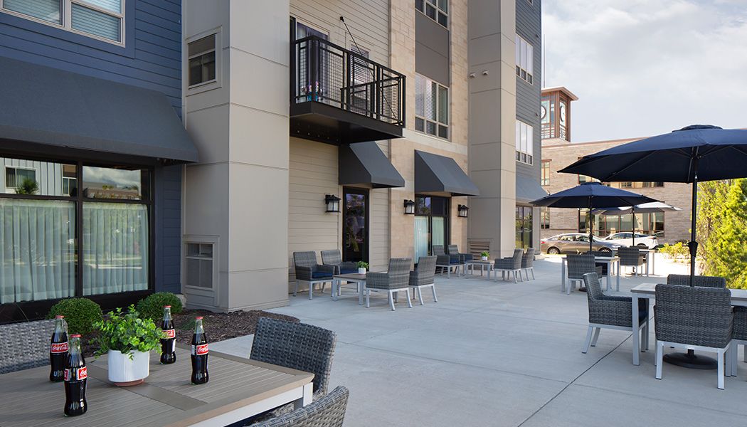 Outdoor patio area with seating and balconies at a residential building.