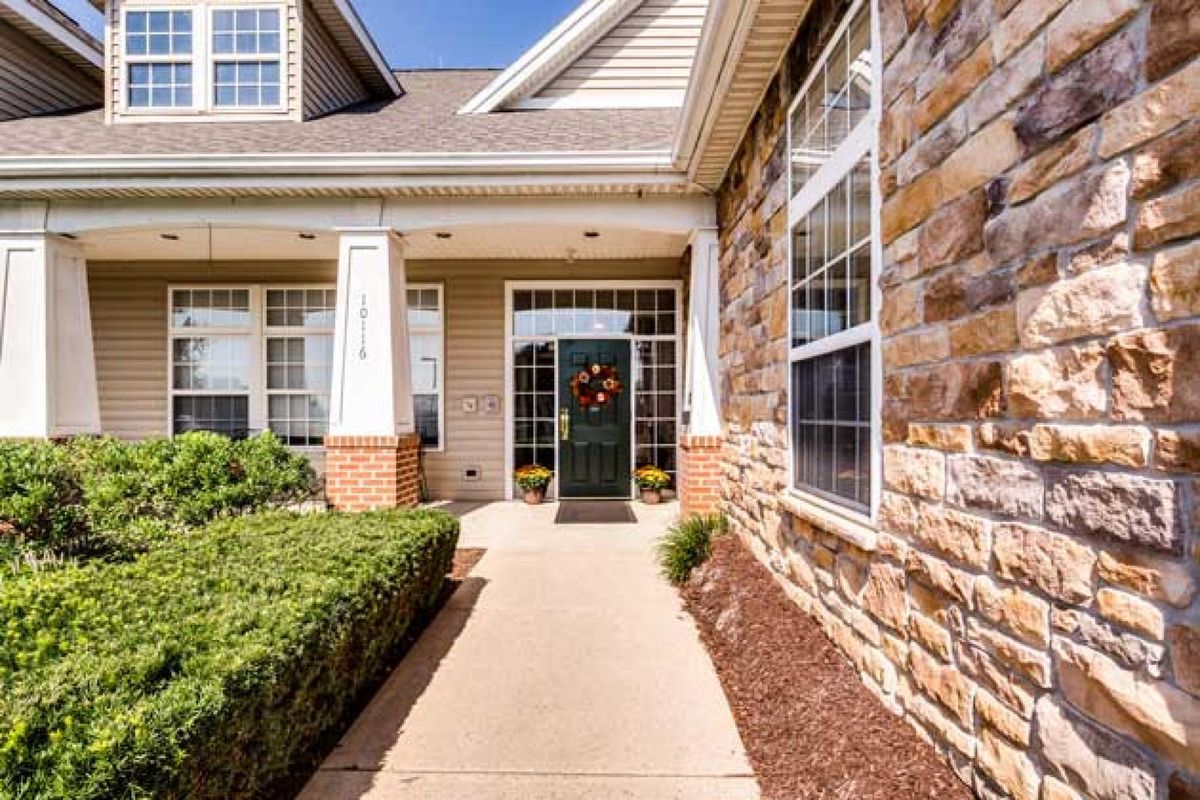 A welcoming entrance to a suburban house with a brick facade and a wreath on the front door.