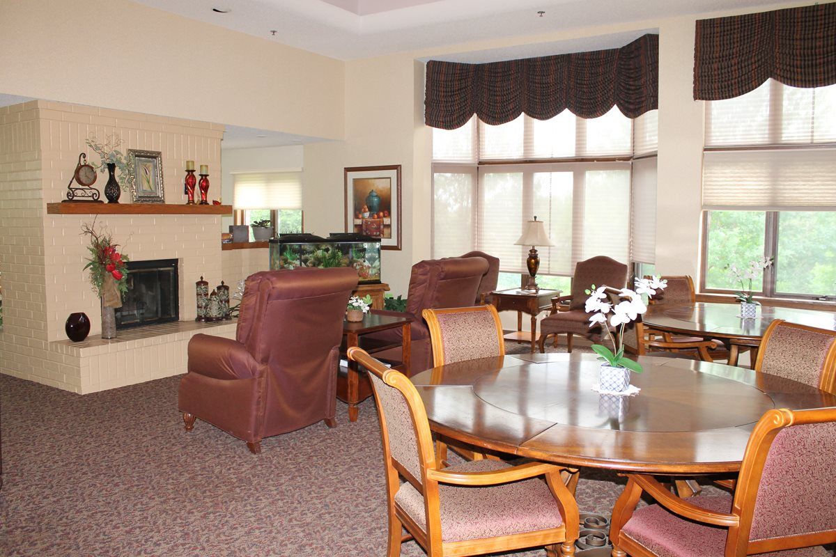 A cozy living room with a fireplace, comfortable seating, and large windows.