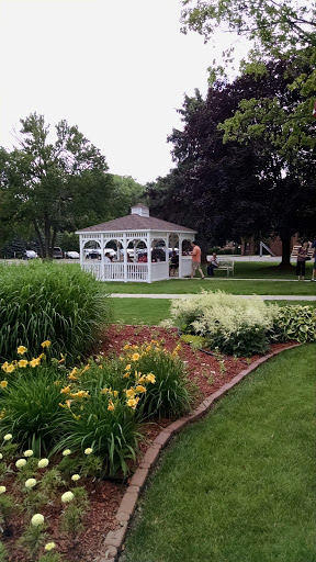 A serene garden scene featuring a white gazebo surrounded by vibrant flowers.