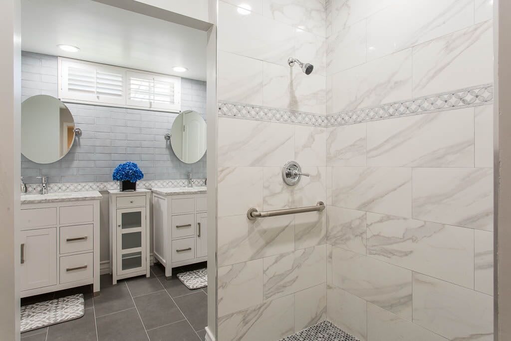 A modern bathroom with a marble-tiled shower and dual vanity.