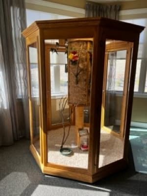 A vintage wooden telephone booth with a payphone inside, set in a sunlit room.