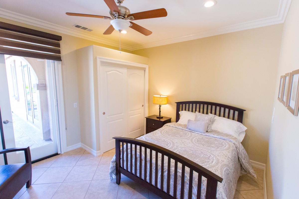A cozy bedroom with a wooden bed, ceiling fan, and closet.
