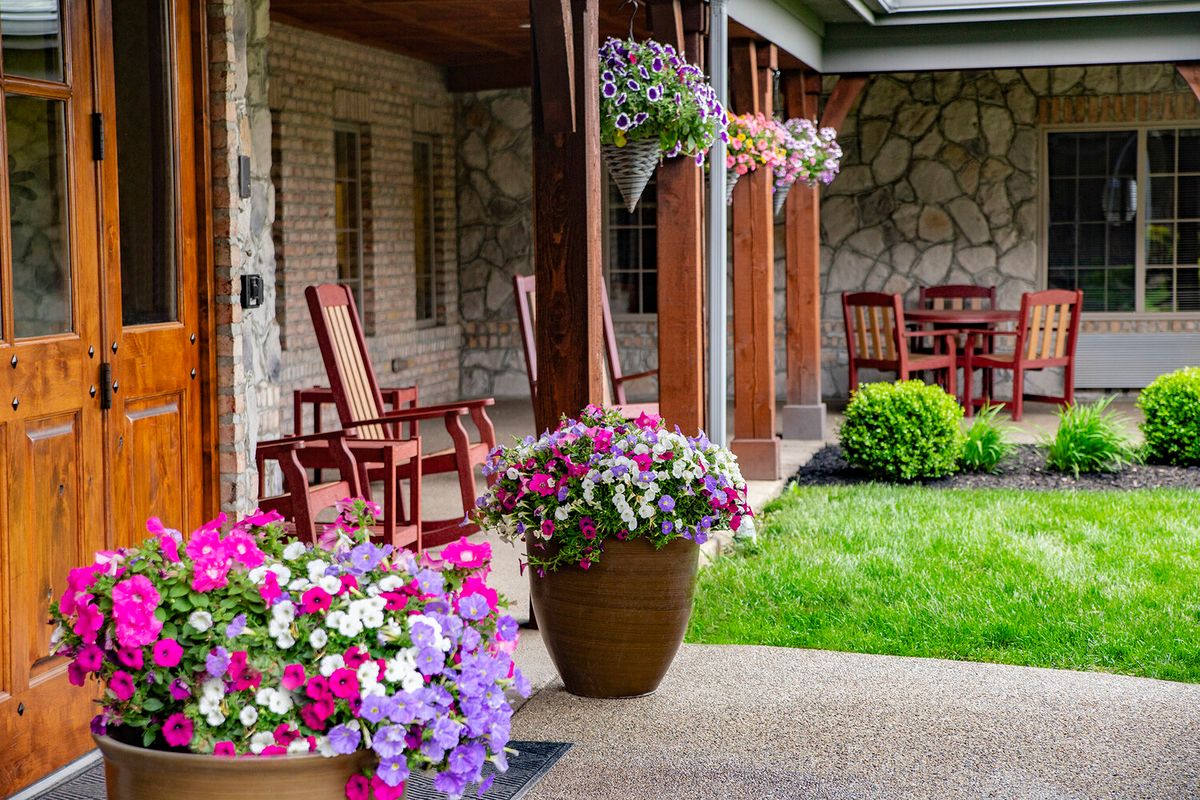 A cozy patio with colorful flowers and wooden furniture, ideal for relaxing in a beautifully landscaped garden.