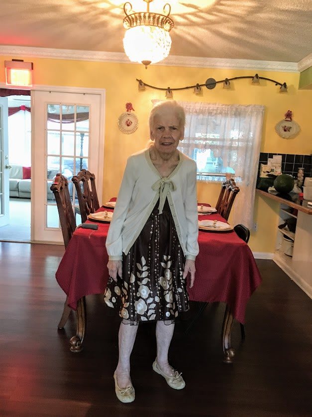 A person stands in a dining room with a table set for a meal.