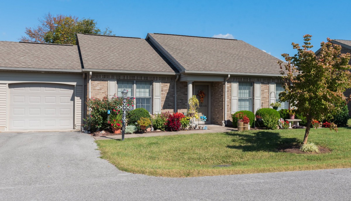A suburban house with a well-maintained lawn and various plants in the front yard.