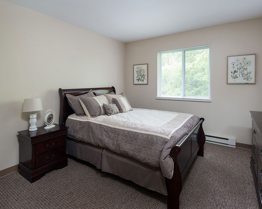 A cozy bedroom with a neatly made bed and a window letting in natural light.