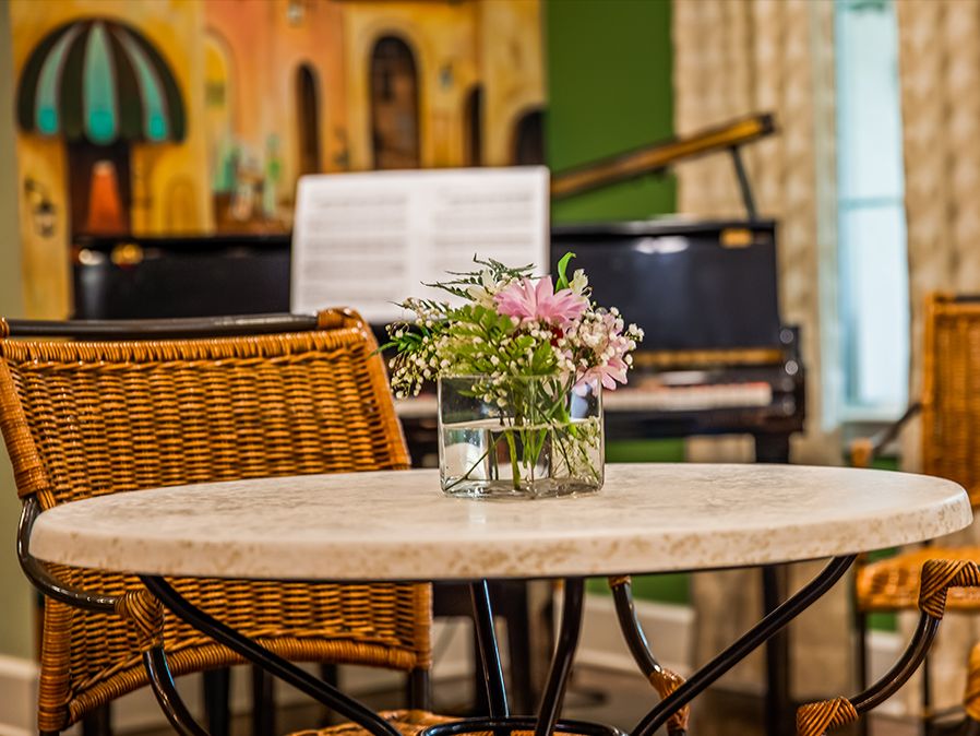 A cozy interior scene with a table centerpiece of flowers, set against a background featuring a piano and sheet music.